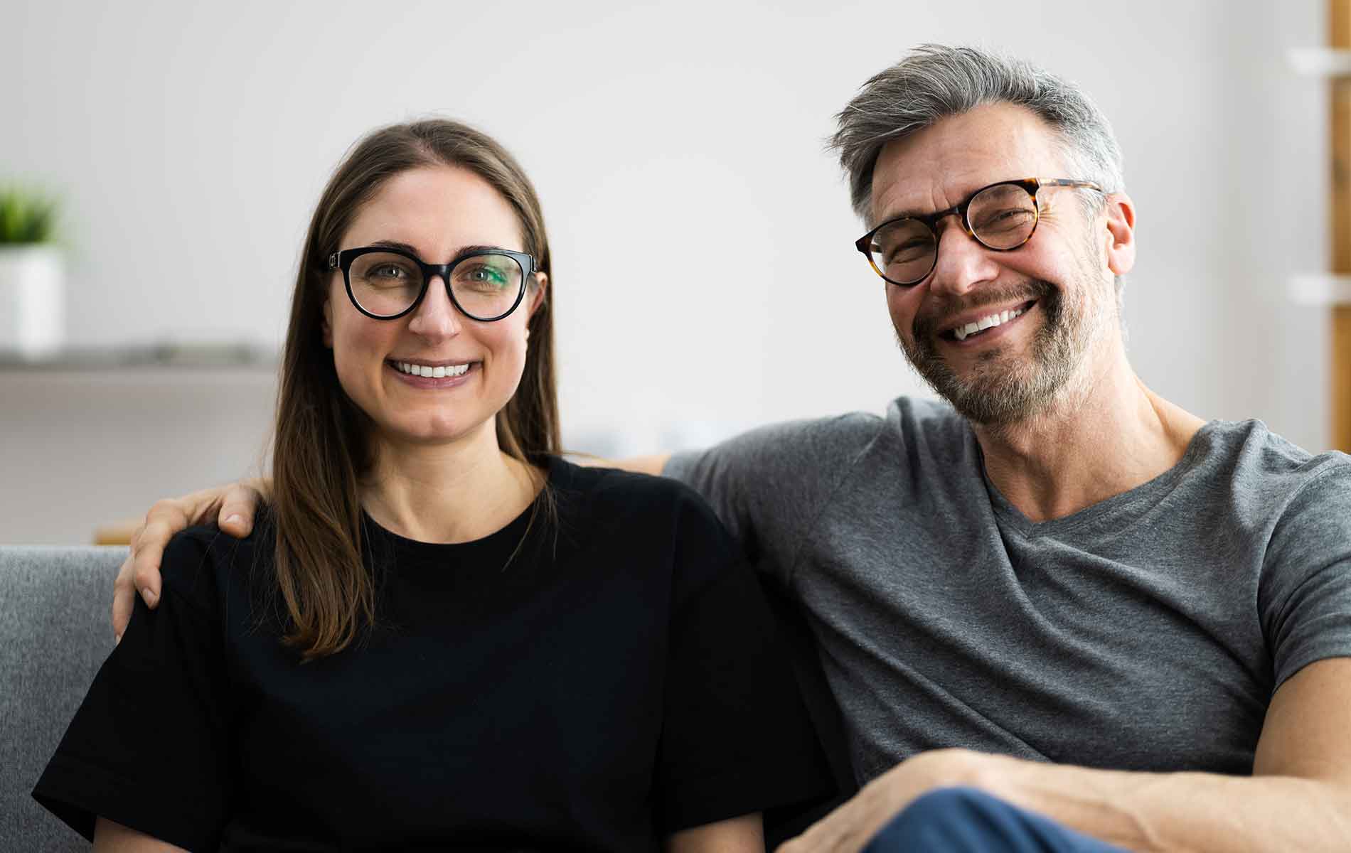 Couple wearing glasses sitting on the sofa.