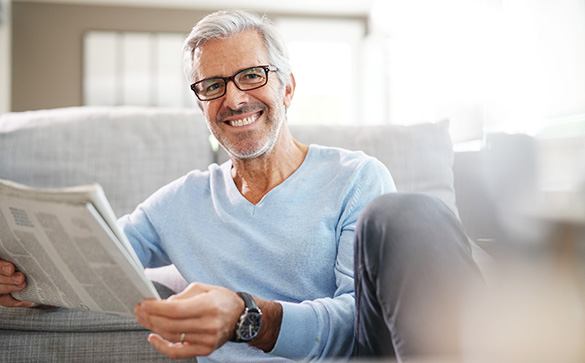 Man wearing glasses reading newspaper 